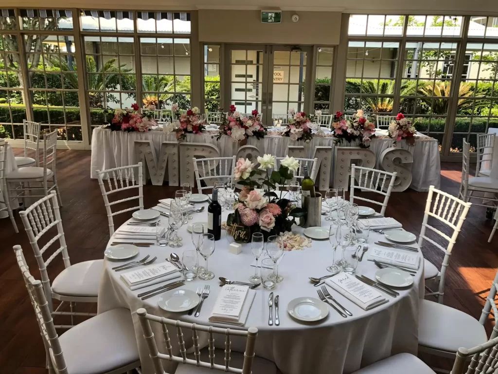 white tiffany chairs and round banquet tables set up at a wedding reception