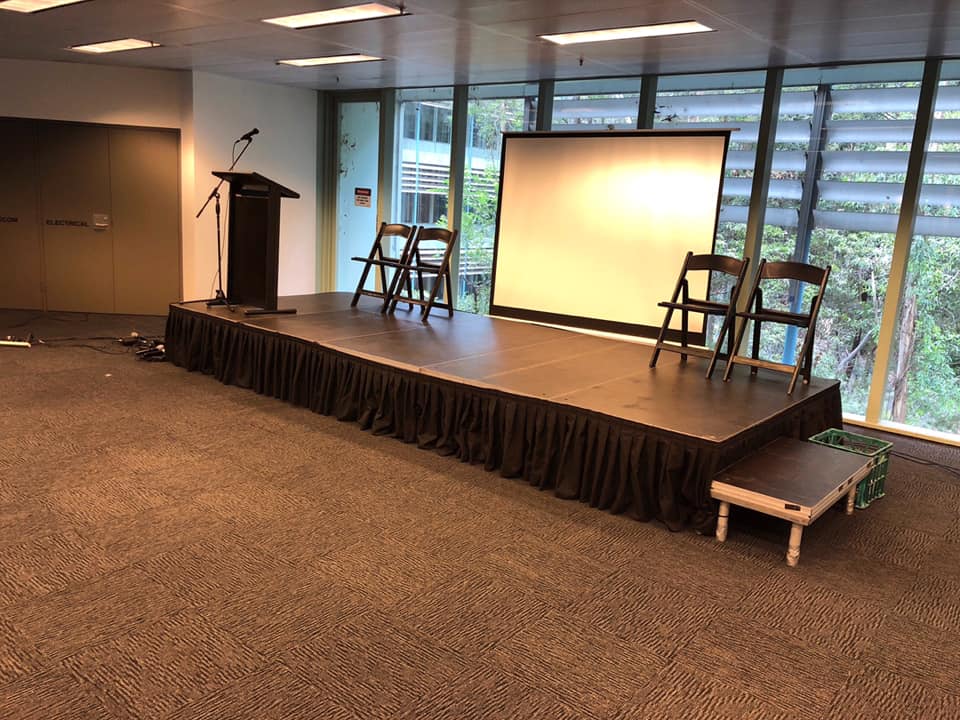 projector, screen, stage, chair and lectern set up on stage