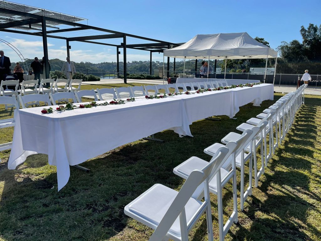 long table with white table linen and white padded folding chair