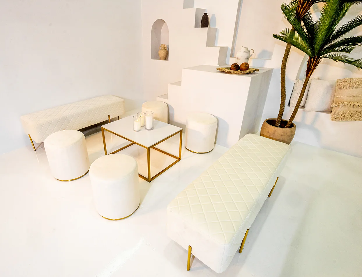 lounge setup with white velvet ottoman stools, benches and gold rectangular coffee table