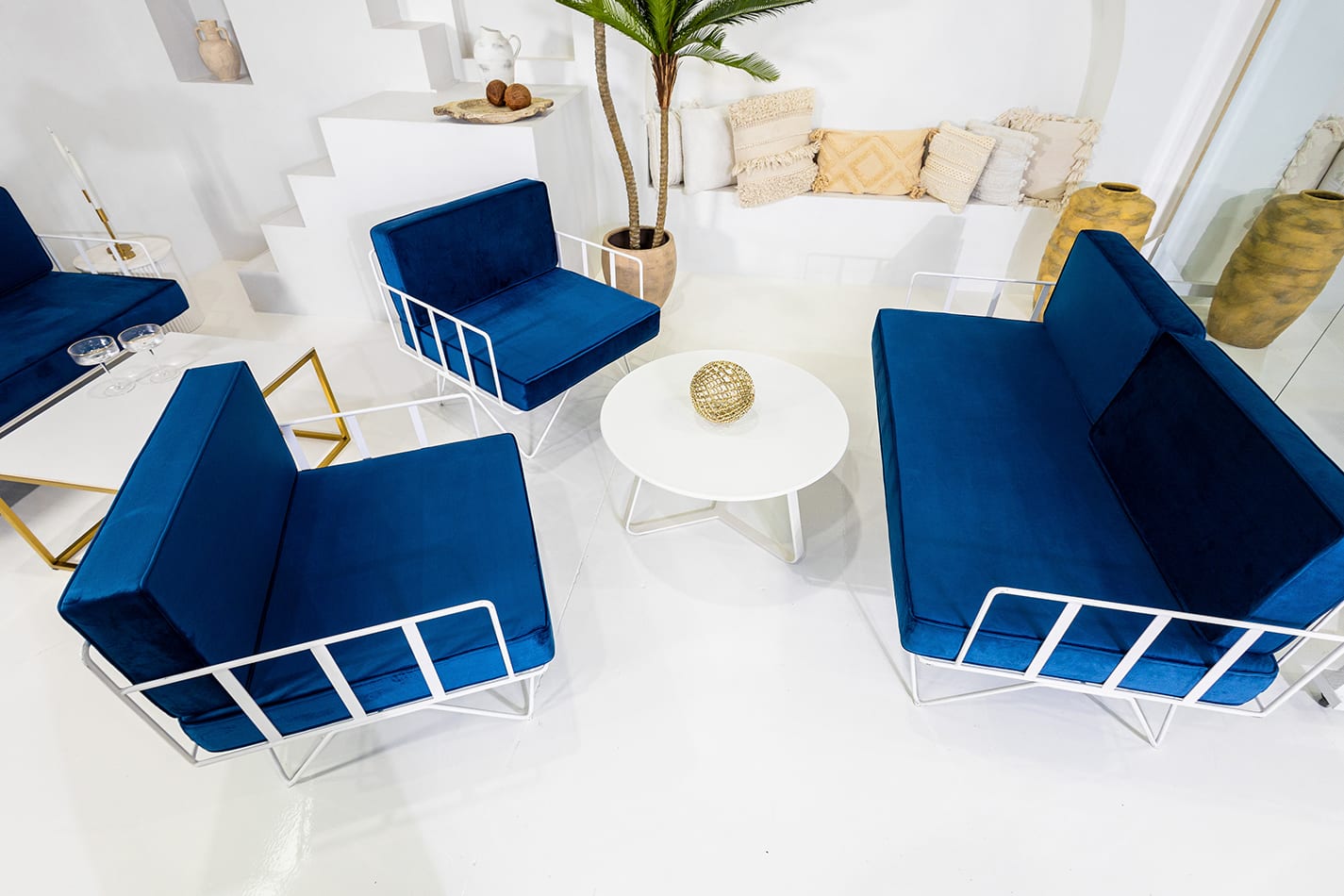 lounge set up of white wire lounge, arm chairs with blue velvet cushions