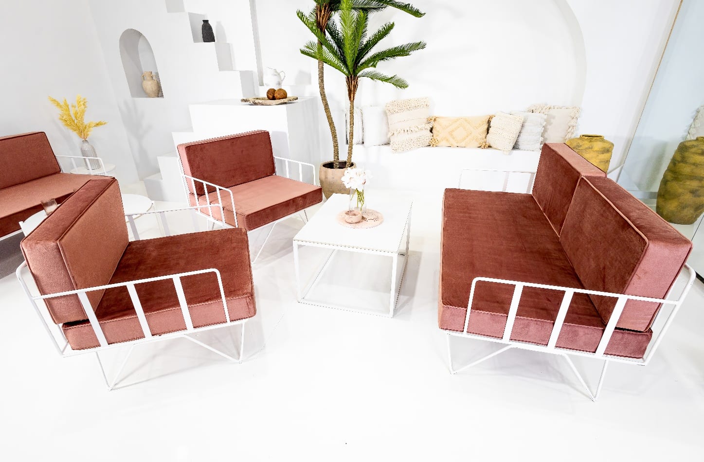 lounge set up with pink sofa and arm chairs with white coffee table