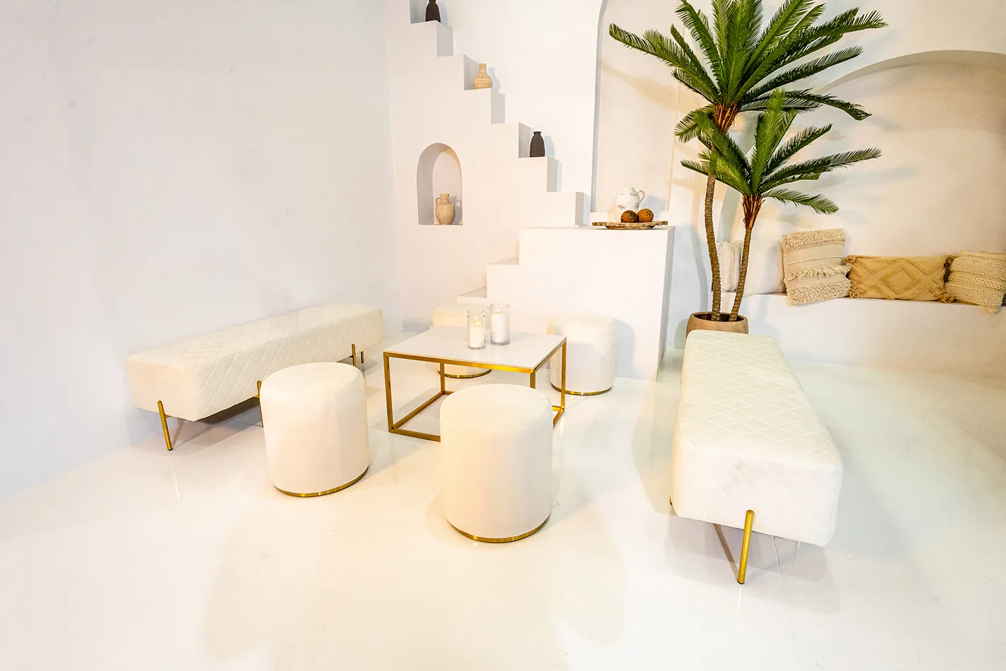 lounge setup with white velvet ottoman stools, benches and gold rectangular coffee table